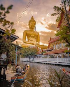 a group of people in a boat in front of a large statue at U&D guest house in Bangkok