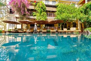 a person walking in front of a hotel pool at Ahoy Hoi An Boutique Resort & Spa in Hoi An
