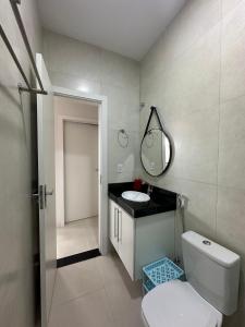 a bathroom with a toilet and a sink and a mirror at Apartamentos novos em condomínio no Caçari in Boa Vista