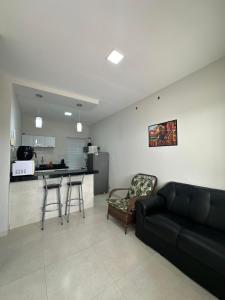 a living room with a black couch and a kitchen at Apartamentos novos em condomínio no Caçari in Boa Vista