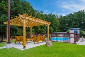 een houten pergola met stoelen en een zwembad bij Econo Lodge Battleboro - Rocky Mount I-95 in Battleboro