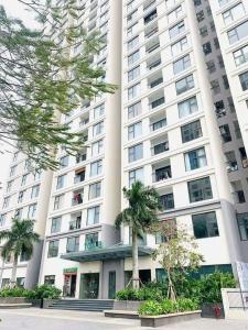 a large white building with palm trees in front of it at Golden sunshine studio-Sea view &Nelflix Free in Ha Long