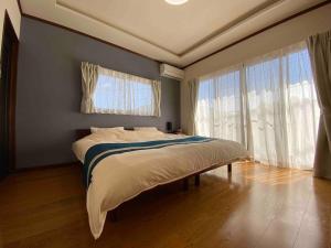a bedroom with a large bed with blue walls and windows at 箱根御泊処-紅葉- 049bH in Hakone