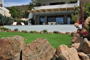 a house with a yard with a rock wall at Aegean Pearl in Áyios Dhimítrios