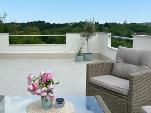 a patio with a table with a vase of flowers at Apartman Perla in Gornji Kraj