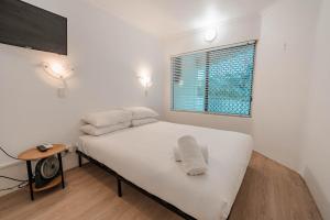 a bedroom with a bed with white sheets and a window at Maroochydore Coastal Suite in Maroochydore