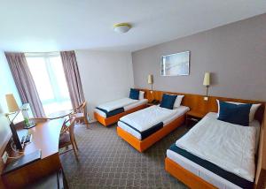 ein Hotelzimmer mit zwei Betten und einem Schreibtisch in der Unterkunft Concorde Hotel Ascot in Düsseldorf