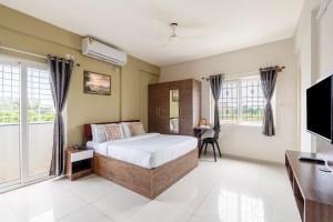 a bedroom with a bed and a desk and windows at Wandr Hotel Brookefield, Bangalore in Bangalore