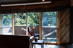 una donna seduta su un divano davanti a una finestra di HAKONE Villa-Rin- 052H a Hakone