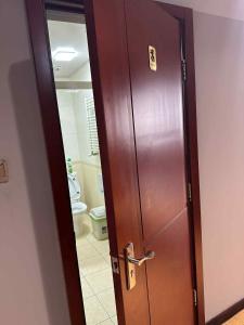 a wooden door in a bathroom with a toilet at The Long White Apartment in Ulaanbaatar