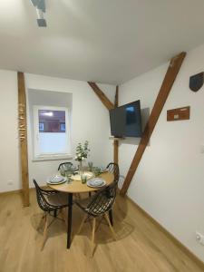 a dining room table with chairs and a tv on the wall at Sea&Wine Apartamenty Darłówko in Darlowko