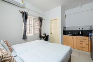 a bedroom with a white bed and a kitchen at Wandr Hotel Brookefield, Bangalore in Bangalore