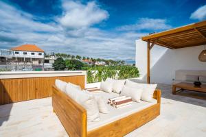 a couch on a balcony with a view of the ocean at Villa Onetti - Luxury Villa with Private Pool, Rooftop & Rice Field Views in Tumbak Bayuh