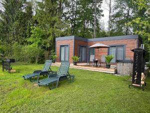 a tiny house in a garden with two lounge chairs at Kempings Jaunzāģeri "Pietura" in Sigulda