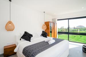 a bedroom with a white bed with a large window at Villa Onetti - Luxury Villa with Private Pool, Rooftop & Rice Field Views in Tumbak Bayuh