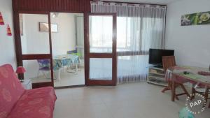 a living room with a couch and a television at Studio Cabine Climatisé tout près de la plage in Le Grau-du-Roi +9 photos