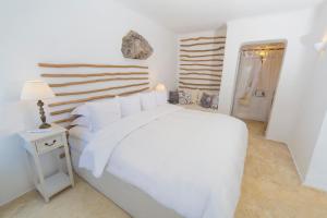 a white bedroom with a white bed and a lamp at Iconic Santorini, a Boutique Cave Hotel in Imerovigli