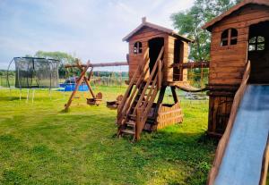 a wooden playground with a slide and a play structure at Wicie - Domki u Anioła in Wicie