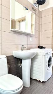 a bathroom with a toilet and a sink and a washing machine at Deus Saranda Apartment in Polisi i Vogël