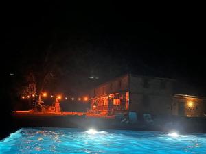 a swimming pool at night with a building and lights at Glamping à la ferme LaBoduBo in Bassoues