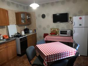 a kitchen with a table and a white refrigerator at Rózsakert Apartman 2 in Poroszló