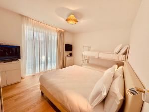 a white bedroom with a bed and a television at Schiavon Beach Palace in Lido di Jesolo