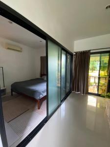 Un dormitorio con una cama y una habitación con ventana. en Green House, en Ko Phangan