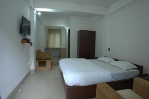 a bedroom with a large bed and a television at Traveller's Hostel by Spirit of Adventure, Dirang in Dirang Dzong