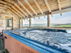 a hot tub in a room with a large window at 5 Bed House -Sleeps 10- Hot Tub - Garden - Parking in Edinburgh