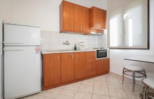 a kitchen with wooden cabinets and a white refrigerator at THEA Panorama Studios in Vourvourou +24 photos