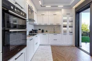 a kitchen with white cabinets and a large window at Villa Arthur in Kassiopi