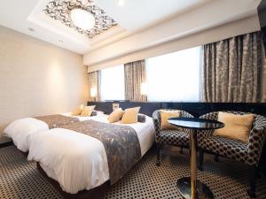 a hotel room with two beds and a table and chairs at APA Hotel Ueno Hirokoji in Tokyo