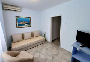 a living room with a couch and a tv at Apartments Mitrovići Miločer in Sveti Stefan