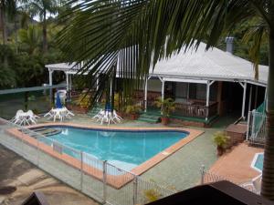 a swimming pool with chairs and a house at The Islands Inn Motel in Airlie Beach