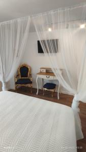 a bedroom with a bed with white curtains and a desk at La fulla verda in San Martín de Tous +35 photos