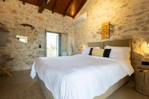 a bedroom with a large white bed in a stone wall at Sophia Areopoli Town Square in Areopoli