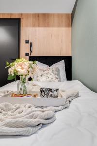 オポーレにあるMuzealna Business Roomsの花瓶に花が飾られたトレイが置かれた白いベッド