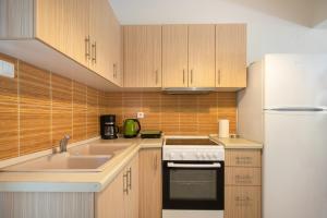 a kitchen with wooden cabinets and a sink and a refrigerator at Sofia Maisonette by RentalsPro - Sani Halkidiki in Sani Beach