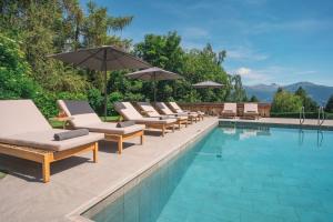 a swimming pool with lounge chairs and umbrellas at Aïda Hôtel & Spa - "Adults Only" Relais & Châteaux in Crans-Montana