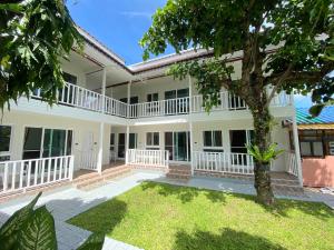 a large white house with a tree in the yard at The Golden Beach Resort Naiyang in Nai Yang Beach
