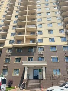 an apartment building with a woman sitting on a bench in front at Жемчужина 59 in Odesa +5 photos