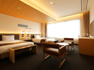 a hotel room with two beds and a window at Kanazawa Sainoniwa Hotel in Kanazawa