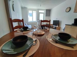 a wooden table with bowls and plates on top of it at Jolie maison centre Ernée in Ernée