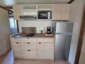 a kitchen with a refrigerator and a microwave at Camping Onlycamp Les Monts du Cantal in Le Claux