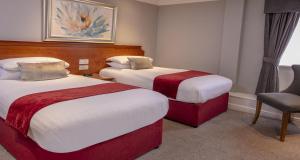 a hotel room with two beds and a chair at Best Western Lichfield City Centre The George Hotel in Lichfield +87 photos