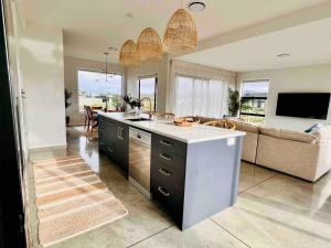 a kitchen and living room with a couch at Sandy Palms - Home Away From Home in Waihi Beach