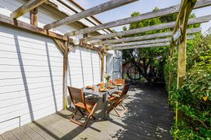 a patio with a table and chairs under a wooden pergola at Nitedo- Maison avec jardin et terrasse - 200m plage et forêt in Mimizan-Plage