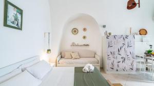 a white bedroom with a bed and a couch at Casetta Carlotta by Rentbeat in Ostuni