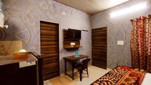帕格瓦拉SYL HOTELS One - Comfortable and Secure Stays的配有电视、桌子和椅子的房间