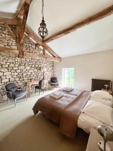 ein Schlafzimmer mit einem großen Bett und einer Steinwand in der Unterkunft Landhuis, oneindig uitzicht, 30ha land, privé zwembad in Auradou